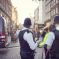 Two police officers in uniform stand on a busy city street near a police van, while pedestrians walk along the cobblestone road—capturing a typical day in the Westminster City Council area.