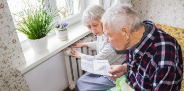 Pensioners looking at bill next to radiator